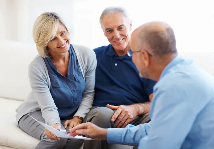 Happy senior couple smiling and listening to financial advisor at home